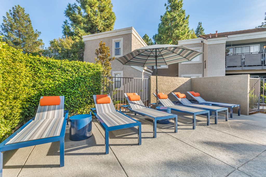 a group of lounge chairs and umbrellas in front of a building