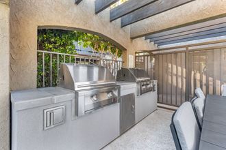 two stainless steel barbecue grills in the patio of a house
