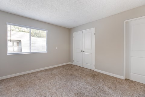 an empty bedroom with white doors and a window