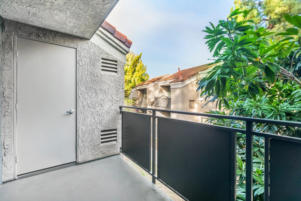 the balcony of a condo with a door and some plants