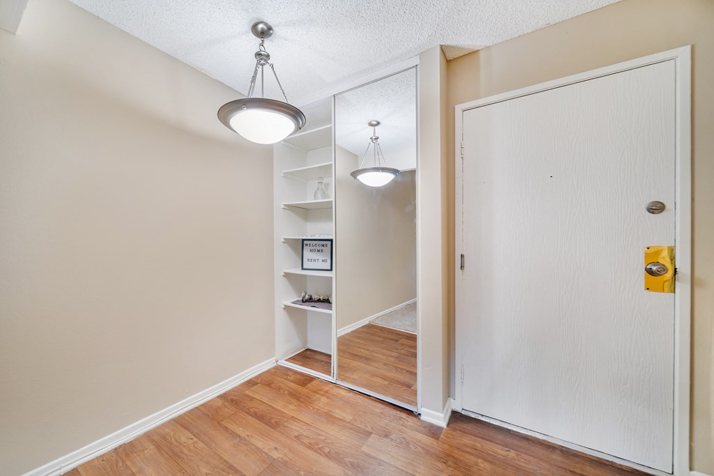 a bedroom with a closet and a door to a hallway with a mirror and lights