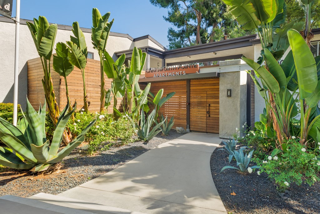 the front of a building with a sidewalk and plants