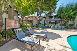 a patio with chairs and umbrellas next to a pool