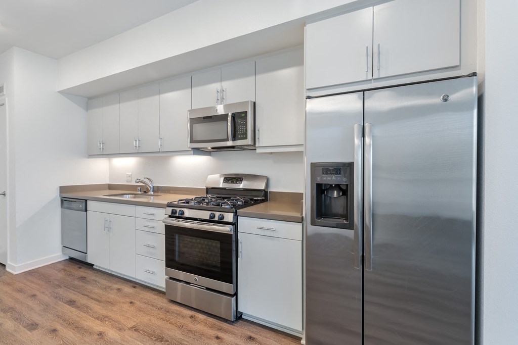 a kitchen with white cabinets and stainless steel appliances and a refrigerator at Metro Gateway, Riverside, 92503