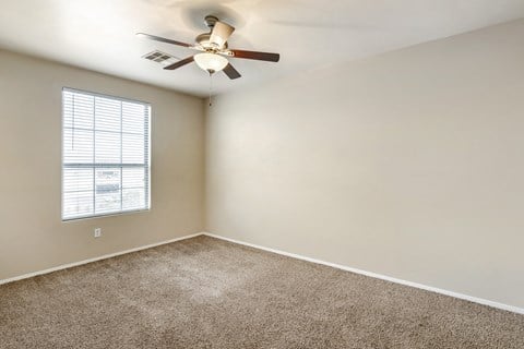 Generously sized bedroom adorned with plush carpeting and equipped with a soothing ceiling fan to enhance your comfort