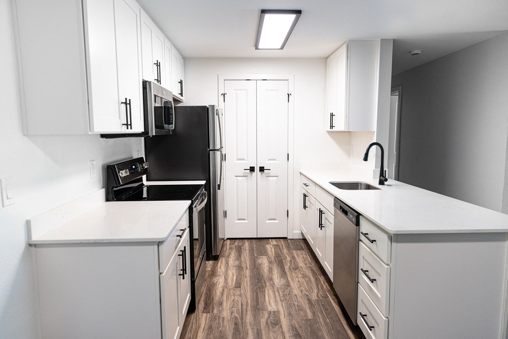 an empty kitchen with white cabinets and a black stove and refrigerator