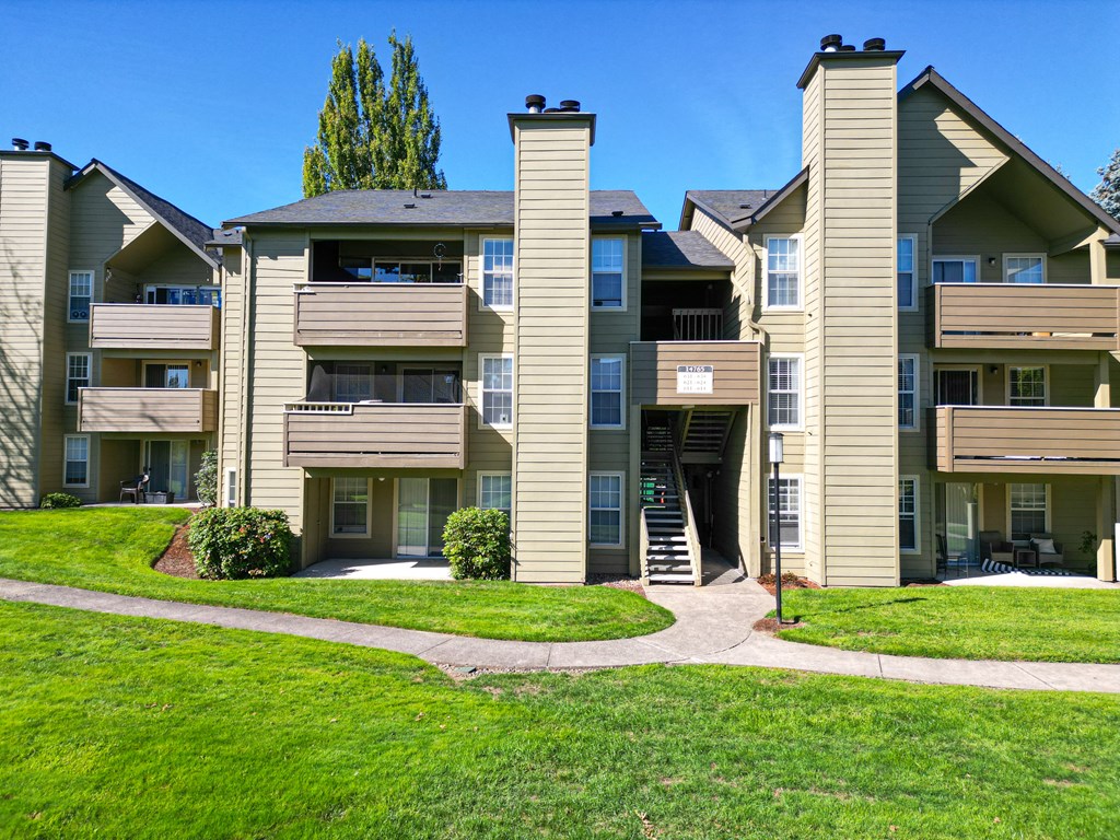 an exterior view of an apartment building with a green lawn