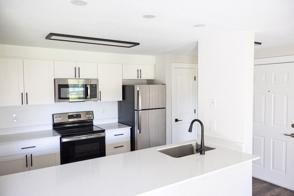 a kitchen with white countertops and a sink and a refrigerator
