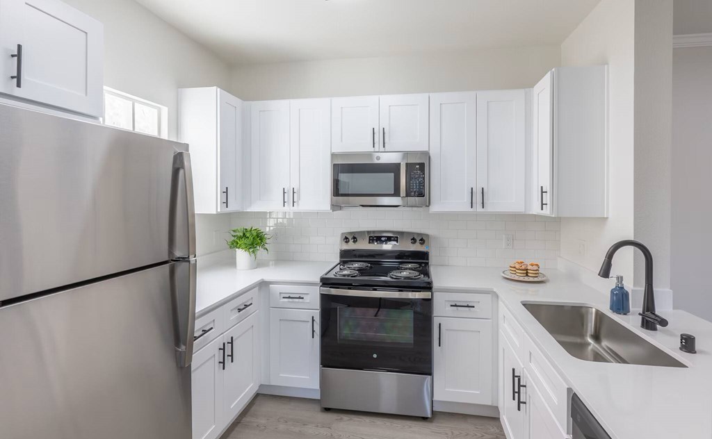 A modern kitchen with white cabinets and stainless steel appliances.