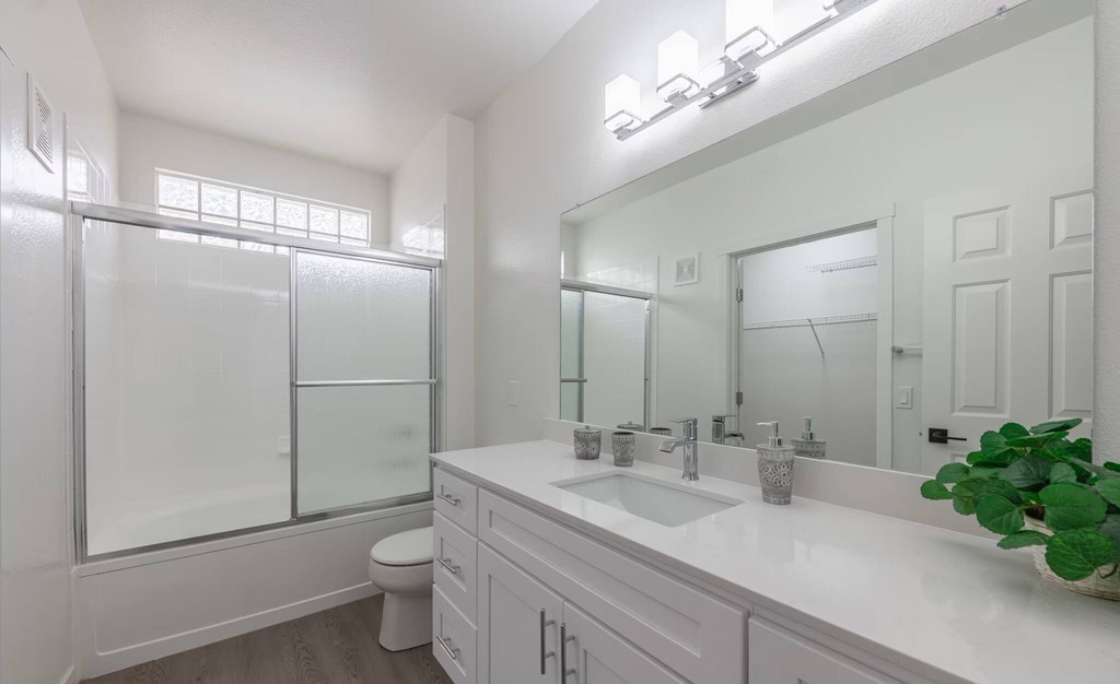 A white bathroom with a toilet, sink, and mirror.