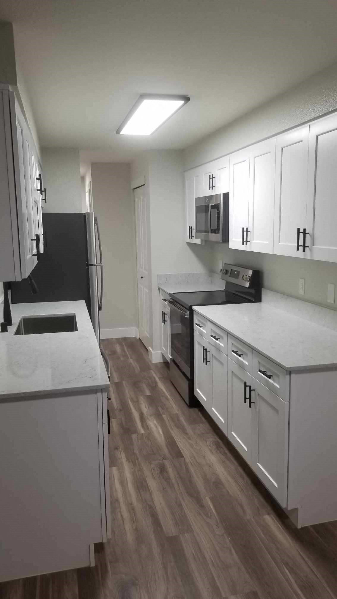 a kitchen with white cabinets and a sink and a refrigerator