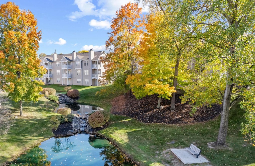 a park with a pond and trees in front of a building