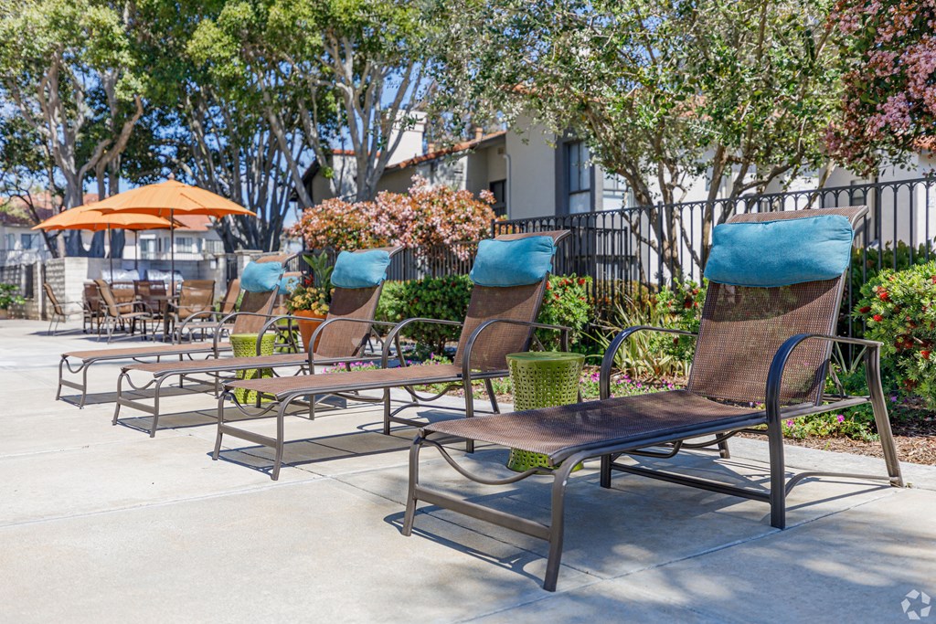 a row of park benches with umbrellas and trees in the background at La Serena, San Diego, 92128