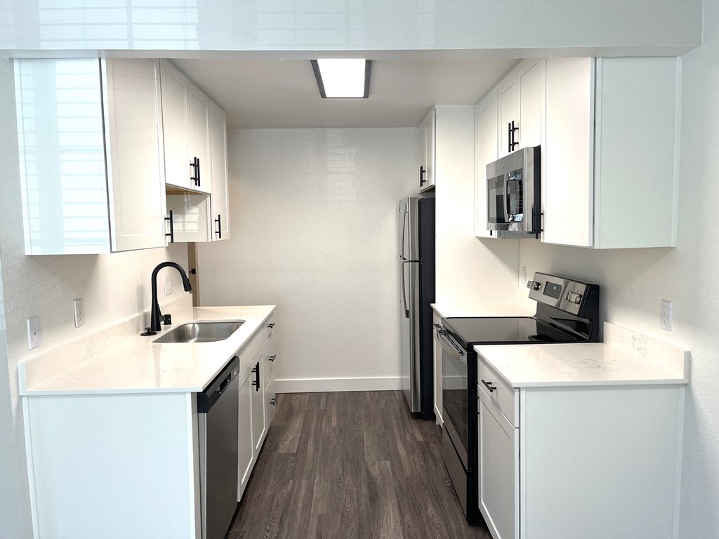 a kitchen with white cabinets and a sink and a refrigerator