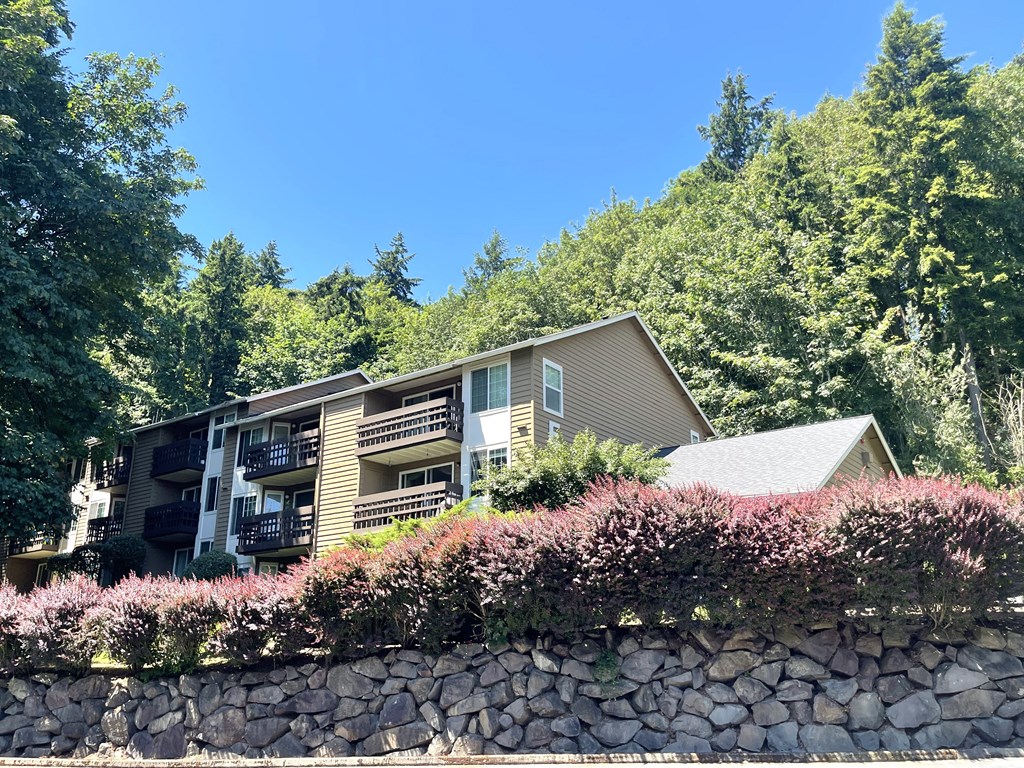 a view of a house with a stone wall and trees