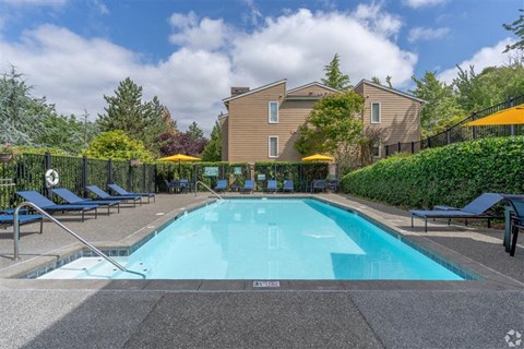 A large swimming pool surrounded by a black fence and lounge chairs. at Kelsey Ridge, Bellevue, 98005