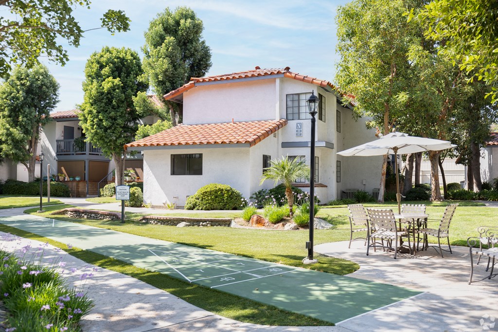 a path with chairs and tables on it in front of a house