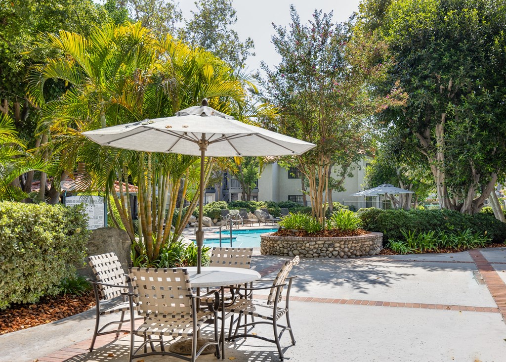 a patio with a table and chairs and a pool in the background