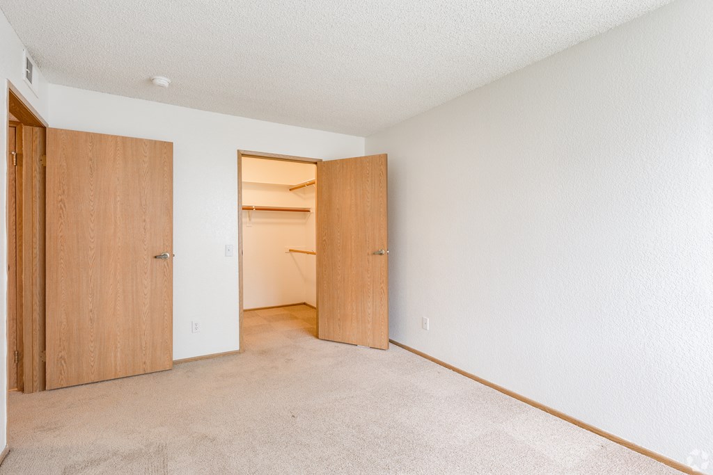 an empty bedroom with a closet and an open door