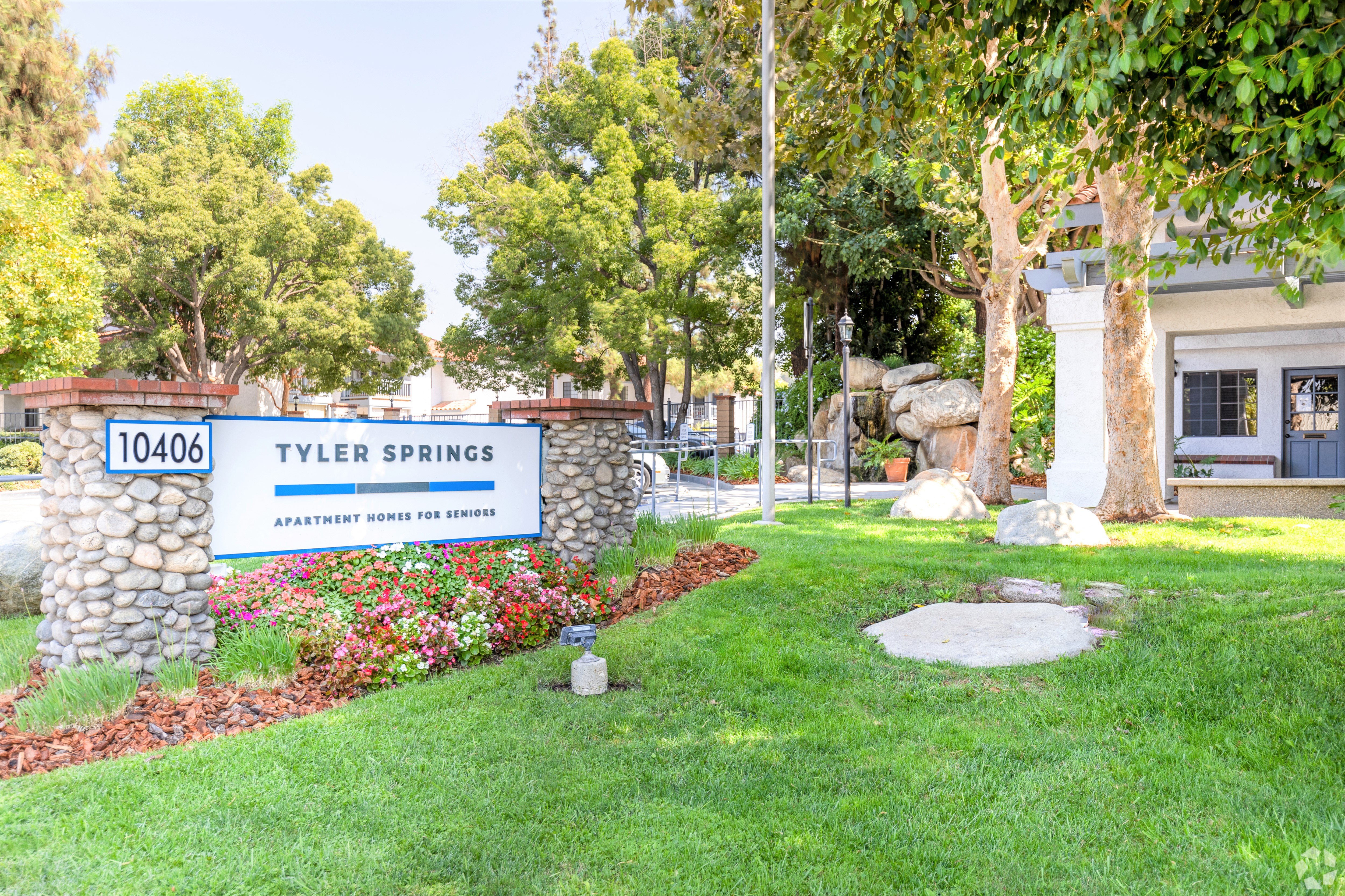 a sign that says tyler springs with a stone wall and trees in the background
