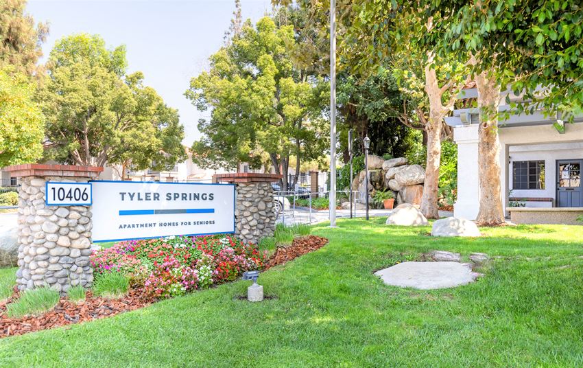 a sign that says tyler springs with a stone wall and trees in the background