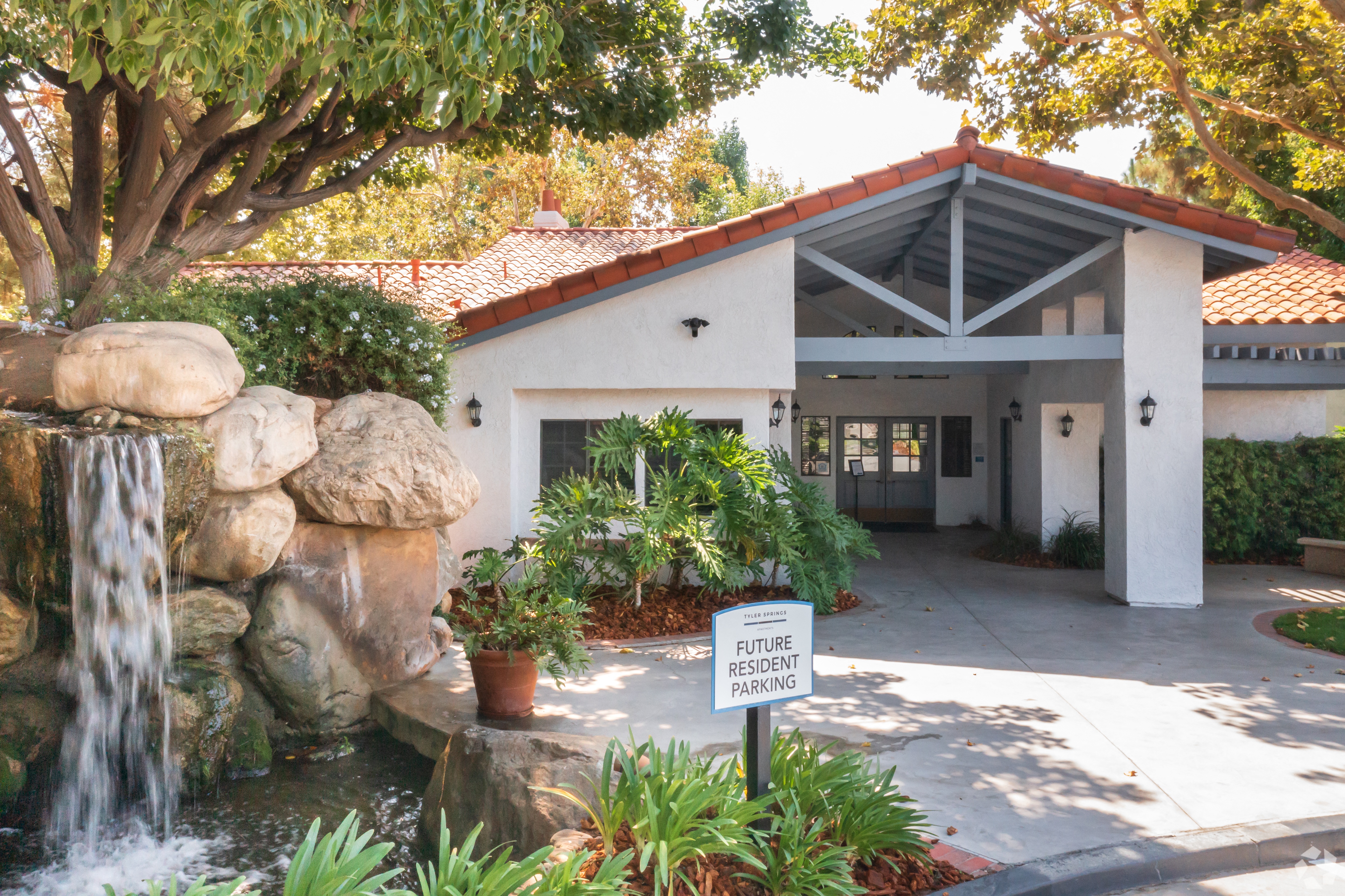 a white building with a red roof and a waterfall in front of it