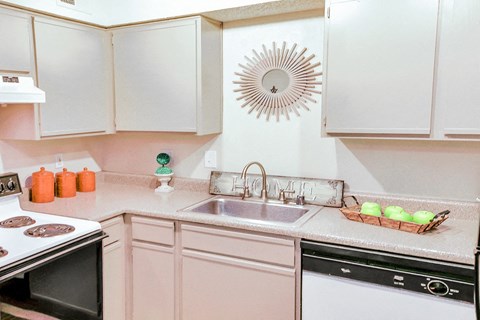 a kitchen with white cabinets and a sink and a stove