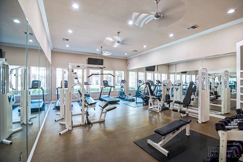 A spacious gym with a variety of equipment and a ceiling fan.