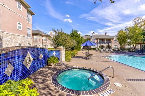 A blue tiled wall surrounds a hot tub in a backyard.