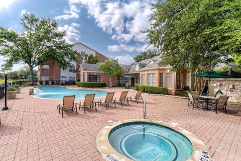 A pool with a hot tub in the middle of a brick patio.