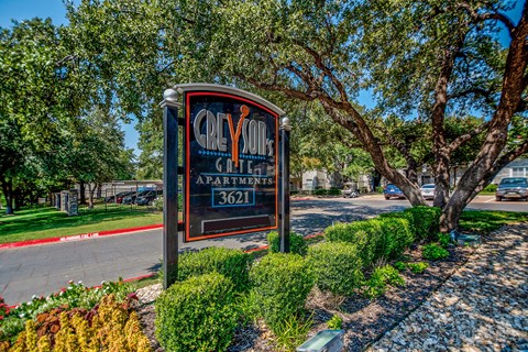 A sign for Clyde Apartments stands in front of a tree.