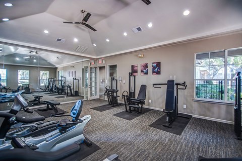 A well-lit gym with a variety of exercise equipment.