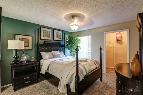 A bedroom with a bed, nightstand, and lamp.