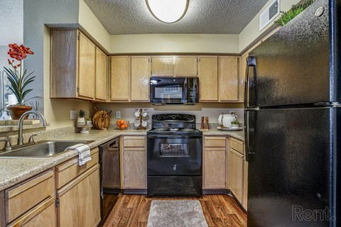 A kitchen with wooden cabinets and a black refrigerator.