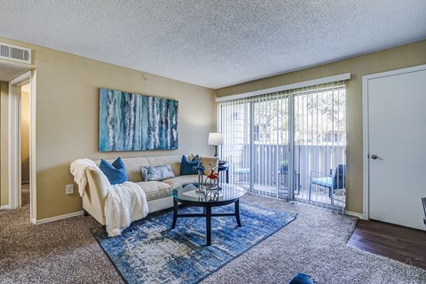 A living room with a couch, a coffee table, and a painting on the wall.