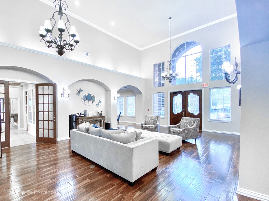 Interior clubhouse view with chandelier, white walls, and hardwood flooring at Gates de Provence Apartments, Dallas, TX