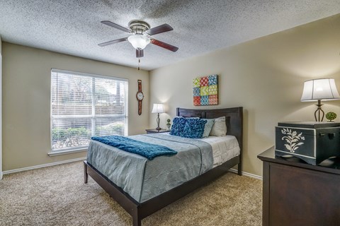 A bedroom with a bed, nightstand, and window.