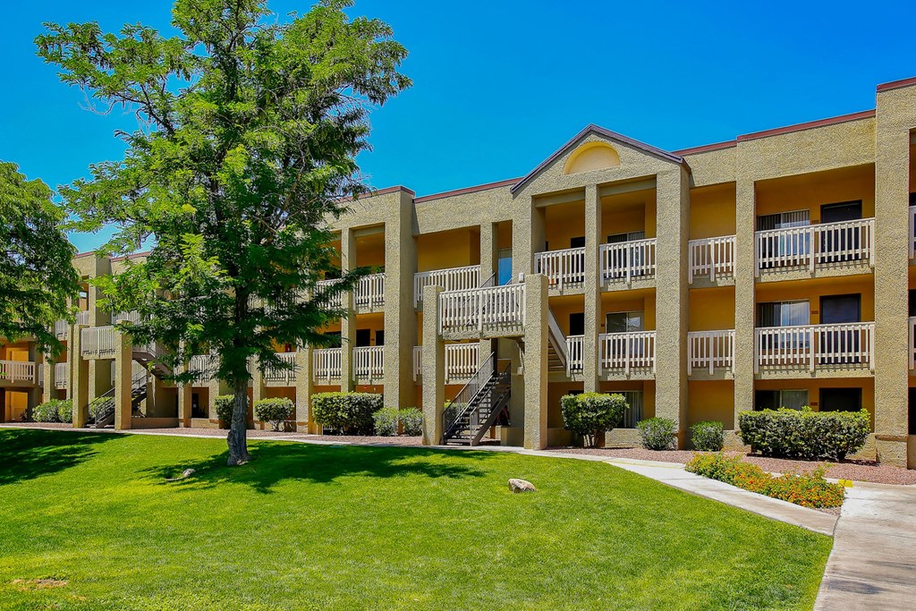 Exterior of apartments with green lawn and trees at Pavilions at Pantano Apartments, Tucson, AZ, Arizona