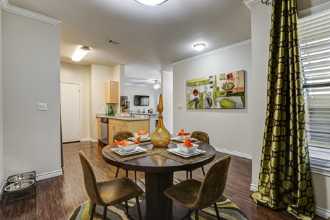 A dining room with a table set for two and a painting on the wall.