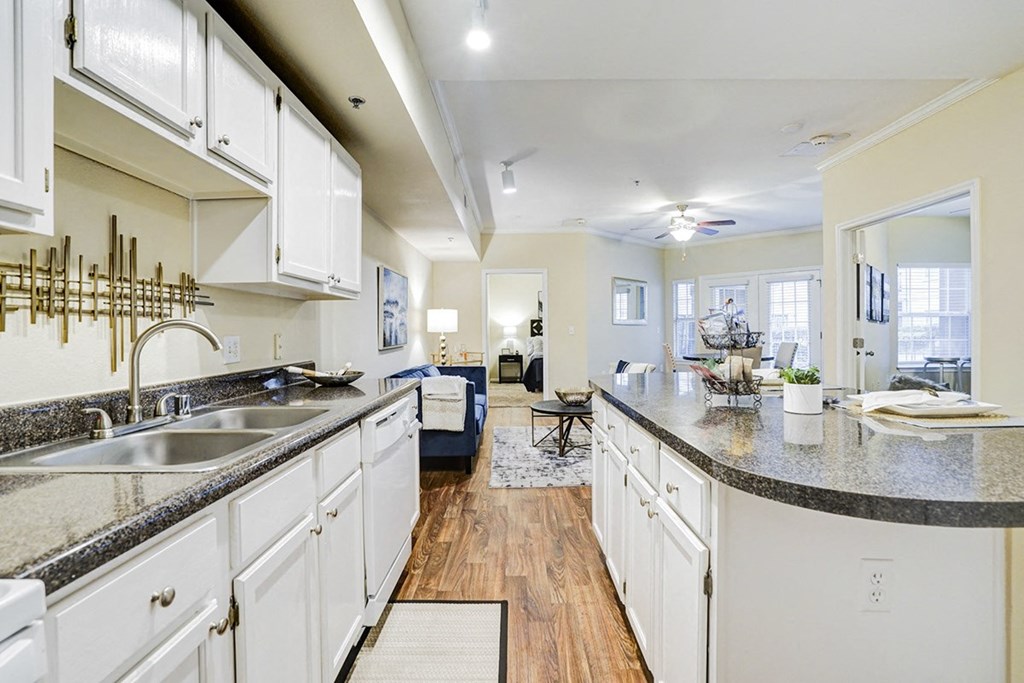 A large kitchen with white cabinets with granite counter tops and natural light at Villas at Katy Trail Apartments, Dallas, 75201