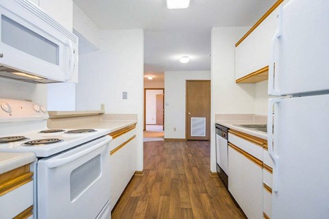 A kitchen with white appliances and wooden floors.