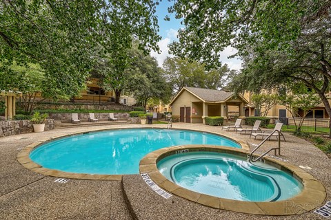 A swimming pool surrounded by trees and a house in the background.