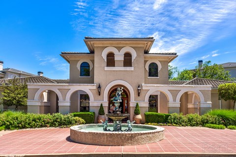 A large house with a fountain in front.