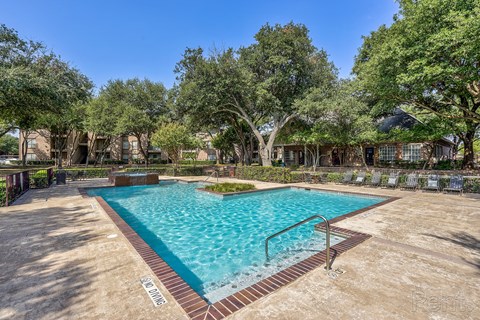 A large outdoor pool surrounded by trees and a fence.