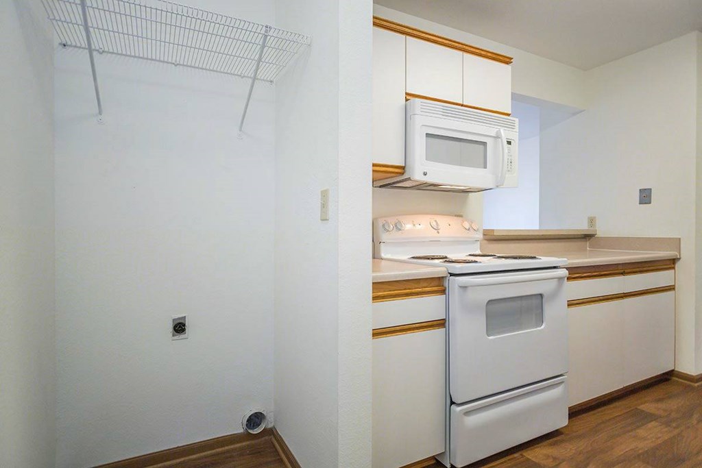 A white oven is in a kitchen with white cabinets at Prairie Commons - 55+ Senior Community Apartments, Lawrence, Kansas