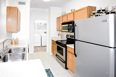 A modern kitchen with a stainless steel refrigerator, microwave, and oven.