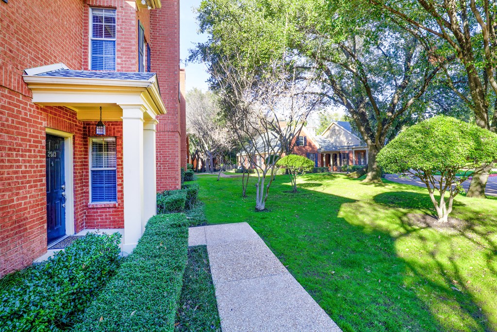Lush green surroundings and walkway at SaddleBrook Apartments, Texas