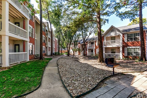 A residential area with apartment buildings and a pebble-covered path.