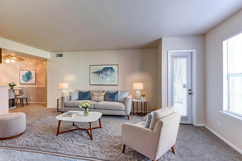 A living room with a white couch, a coffee table, and a painting on the wall.