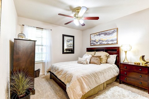 A bedroom with a bed, dresser, and ceiling fan.
